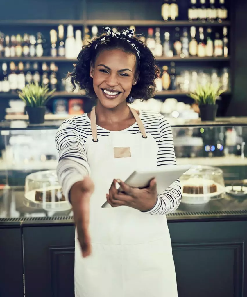 Smiling hostess offering a handshake in a cafe